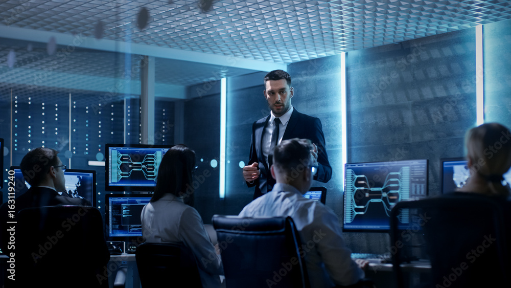 Aufkleber supervisor holds briefing for his employees in system control center full of monitors and servers. p