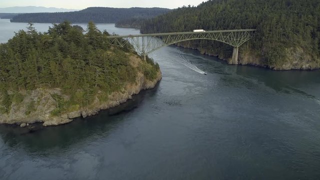 Helicopter Filming Boat Cruising Under Large Pacific Northwest Bridge with Truck Delivering Package Driving Across