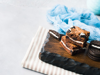 Cream cheese chocolate layer brownies with cookies on wooden serving board