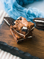 Cream cheese chocolate layer brownies with cookies on wooden serving board