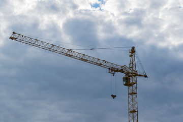 Yellow tower hydraulic crane that builds on a background of dark blue sky. Mock up. Ready for advertising