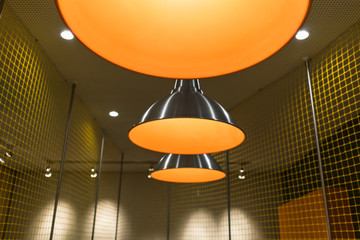 Group of hanging lights in a row with an orange blossom. Modern elegant design of the meeting room. Ideal symmetry of light bulbs in the office.