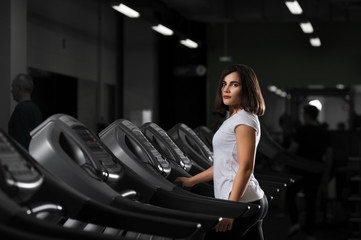 Naklejka na ściany i meble Young brunette girl exercising on treadmill.