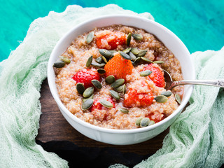 Quinoa porridge with strawberries and pumpkin seeds in bowl. Light dairy and gluten free breakfast