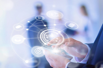 Portrait of young businessman using mobile in office with colleagues in the background, modern icon