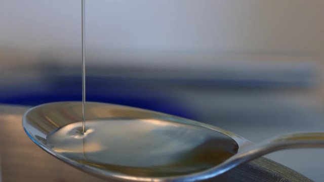 A woman measures out tablespoonfuls of oil and pours them into a steel bowl - closeup