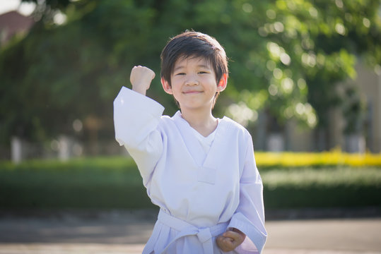 Cute Asian child in white kimono during training karate in summer outdoors