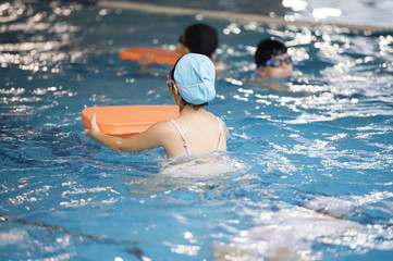 Child holding a floating board swim in the pool