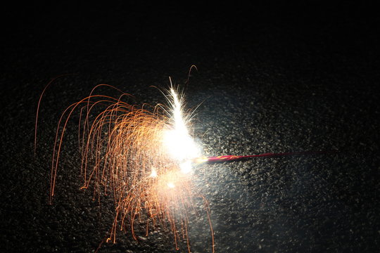 A child playing with burning sparkler firework. Motion blur effect over black background. Selected Focus. Light trail