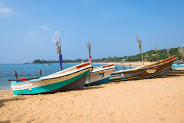 Fototapeta na wymiar At the beach of Unawatuna, one of the major tourist spots in the south west of Sri Lank. Outrigger and traditional fishing boats on the beach