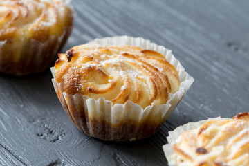 Sweet tasty mufins with sugar powder close up on wooden background