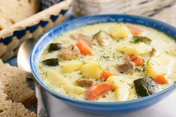 Potato soup with turkey and zucchini on wooden table.