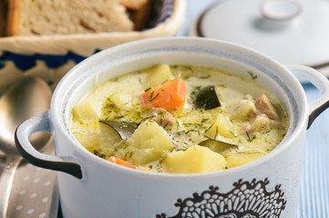 Potato soup with turkey and zucchini in blue kitchen pot.