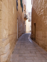 Fototapeta na wymiar Narrow street in Mdina Malta old city. Maltese sandstone architecture