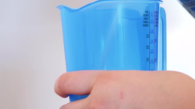 A blue plastic measuring jug is filled with milk - closeup