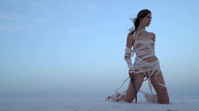 Mummy woman kneels in the desert