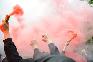 Fototapeta Soccer fans holding up fireworks with thick red smoke of bengal fire obraz