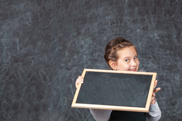Portrait of happy little schoolchild on background of backboard in school