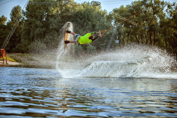 Wakeboarder young athlete, he jumped over the water creating a splash.