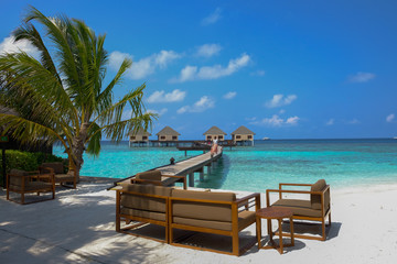 Fototapeta na wymiar Enjoy, have a seat and relax in the water bungalows deck at the summer days. Maldive Islands.