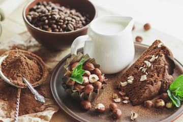 Piece of chocolate cake, mint leaves, hazelnuts and jar with milk