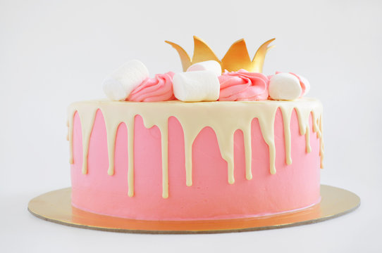 Cake for little girl with pink cream, white chocolate, decorated with marshmallow and gold crown. For little princess. Picture for a menu or a confectionery catalog.