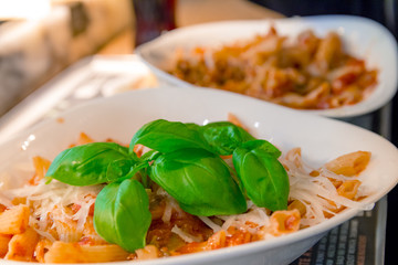 Penne pasta with tomato sauce and decorated with a mint leaf