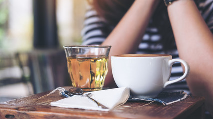 A woman sitting in cafe with cups of hot coffee and tea on vintage wooden table in cafe