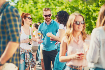Group of friends drinking, chatting and having a good time at outdoor party