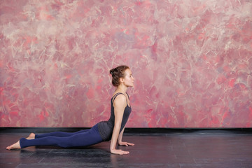 Woman practicing and stretching in a yoga studio. Basic yoga pose: upward facing dog or urdhva mukha svanasana.