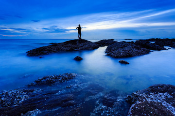 Rock with silhouette girl over smooth foggy water level Slow Shutter Speed