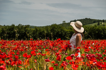 White dressed woman in a poppies field