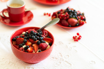 Healthy breakfast: cottage cheese with sour cream, strawberry, raspberry and blueberry, espresso, cherry cheesecake and plate of fresh ripe berries on white table cloth. Selective focus