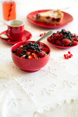 Healthy breakfast: cottage cheese with sour cream, strawberry, raspberry and blueberry, espresso, cherry cheesecake and plate of fresh ripe berries on white table cloth. Selective focus