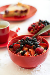 Healthy breakfast: cottage cheese with sour cream, strawberry, raspberry and blueberry, espresso, cherry cheesecake and plate of fresh ripe berries on white table cloth. Selective focus