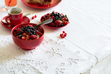 Healthy breakfast: cottage cheese with sour cream, strawberry, raspberry and blueberry, espresso, cherry cheesecake and plate of fresh ripe berries on white table cloth. Selective focus