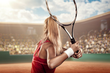 back view of a female tennis player on tennis court ready to hit a ball