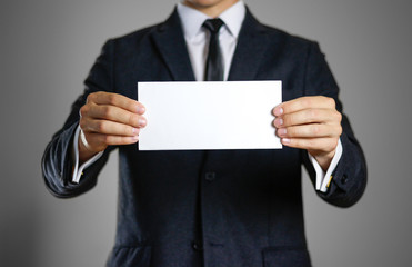 A man in black suit holding blank clear white of the sheet. Closeup. Isolated