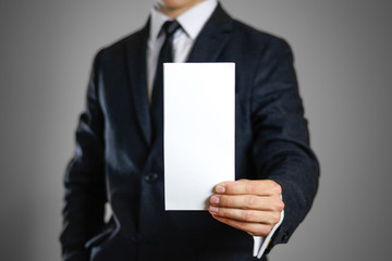 A man in black suit holding blank clear white of the sheet. Closeup. Isolated