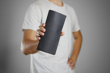 A man in a gray t-shirt holding blank clear black of the sheet. Closeup. Isolated