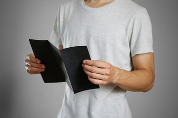 A man in a gray t-shirt holding blank clear black of the sheet. Closeup. Isolated