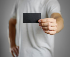 A man in a gray t-shirt holding blank clear black of the sheet. Closeup. Isolated