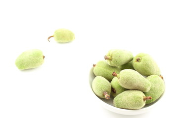 fresh green almond fruits in a small white bowl
