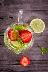Fresh lemonade with strawberries, lemon and ice in a glass jug. Top view