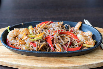 Wok spaghetti with red and green peppers and shrimps. Restaurant food. Served with chinese chopsticks