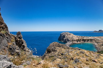 Fototapeta na wymiar Bay and shore of the city of lindos. Blue water and wonderful beaches of Rhodes island. View from the hill below the acropolis.