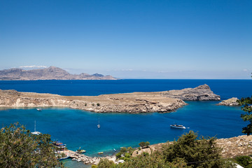 Fototapeta na wymiar Bay and shore of the city of lindos. Blue water and wonderful beaches of Rhodes island.
