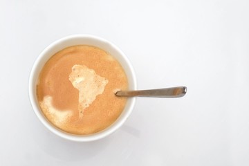 A cup of hot coffee with a map of South (Latin) America on the coffee cream