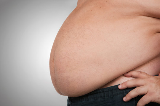 Obesity, close up of fat mans belly, isolated on gray background with copy space