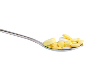 Spoon full of white and yellow medicine tablets on white background, healthcare and medical concept.